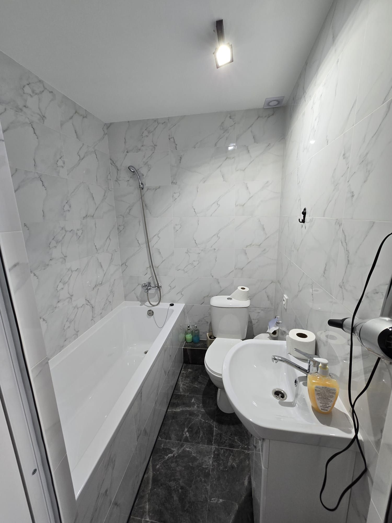 Une salle de bain avec une baignoire, des toilettes et un lavabo, le tout avec des murs en marbre.