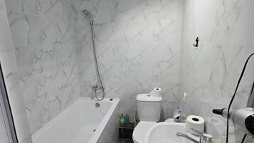Une salle de bain avec une baignoire, des toilettes et un lavabo, le tout avec des murs en marbre.