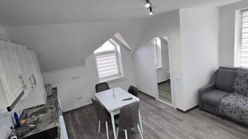 Un espacio habitable compacto con kitchenette, comedor y zona de estar.