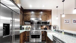 Una cocina moderna con electrodomésticos de acero inoxidable, armarios de madera y encimera de granito.