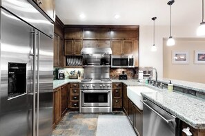 Eine moderne Küche mit Edelstahlgeräten, Holzschränken und einer Arbeitsplatte aus Granit.
