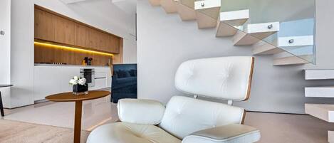 A modern interior with a sofa, a round table, and a staircase.