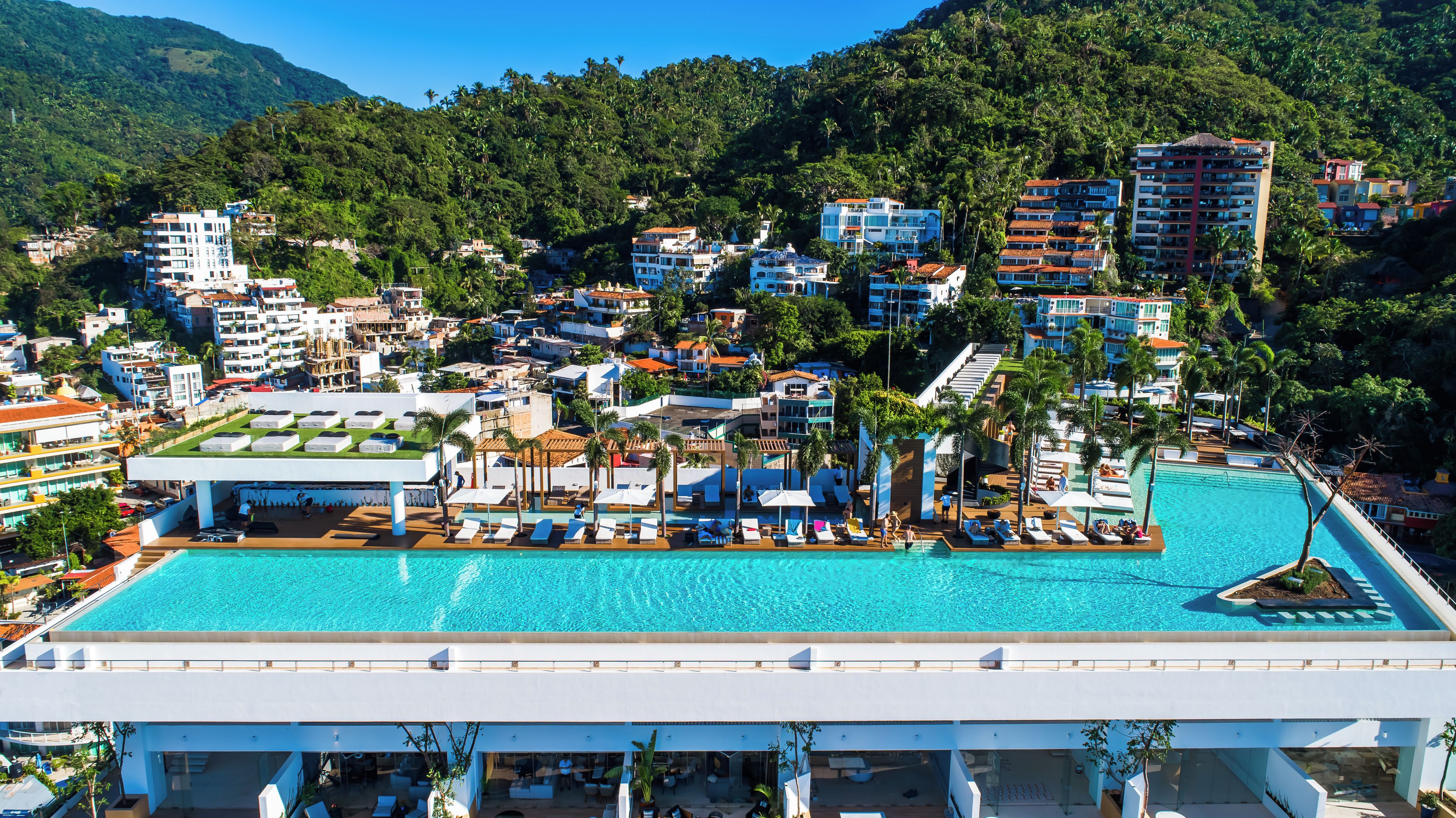 Un resort con una amplia piscina, varias edificaciones y abundante vegetación.