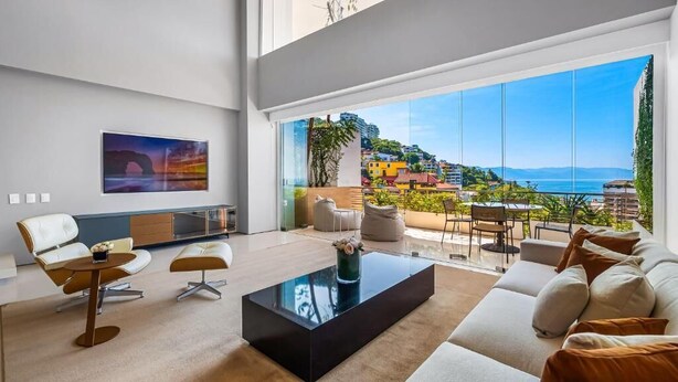 Ein modernes Wohnzimmer mit großem Fenster, einer Couch, einem Couchtisch und einem Gemälde an der Wand.