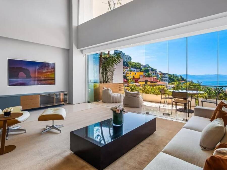 Ein modernes Wohnzimmer mit großem Fenster, einer Couch, einem Couchtisch und einem Gemälde an der Wand.