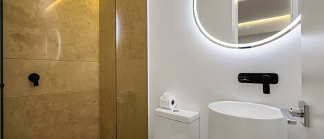 A modern bathroom with a toilet, sink, and a mirror with a circular light.
