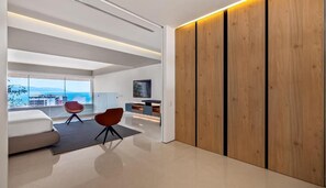 Una sala de estar moderna con un ventanal grande, un sofá, una butaca roja y un separador de madera.