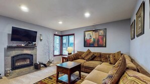 Una sala de estar con chimenea, un sofá, un televisor y un cuadro en la pared.