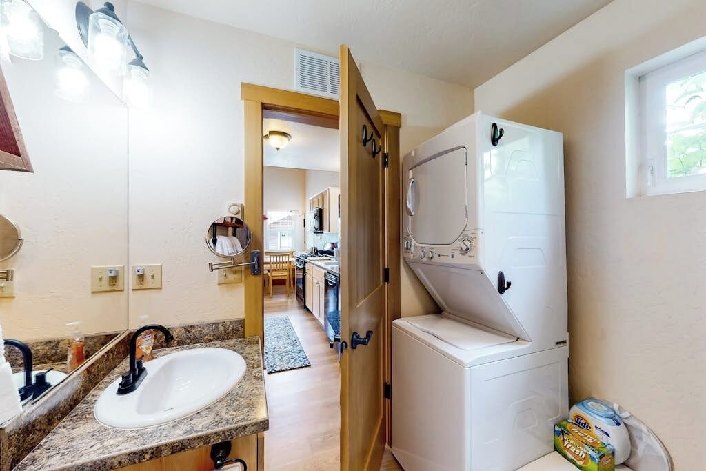 A bathroom with a sink, mirror, and a white washing machine.