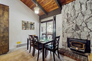 Ein Essbereich mit Tisch und Stühlen, einer Steinwand und einem Kamin.