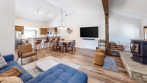 Un soggiorno moderno con un divano, una zona pranzo con sedie, una cucina sullo sfondo e un camino.
