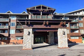 A multi-story hotel with a stone entrance, balconies, and a clear sky. - Beautiful & Convenient Suite Close to Activities w/Shared Pool & Hot Tub, WiFi (Mammoth Lakes)
