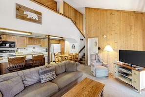 A cozy living area with a sofa, TV stand, and wooden walls. - Fantastic Vacation Retreat w/Shared Pool, Hot Tub, Sauna + Free WiFi (Mammoth Lakes)