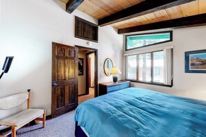 Ein Schlafzimmer mit einem großen Bett, einer hölzernen Bank, einer Tür, einem Fenster und einer Lampe.