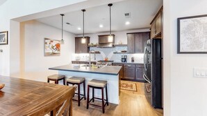 A modern kitchen with a central island, pendant lights, and wooden cabinetry. - Luxe, Modern Townhome w/ Mountain Views & WiFi - Close to Golf & Skiing (Mammoth Lakes)
