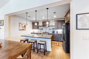 A modern kitchen with a central island, pendant lights, and wooden cabinetry. - Luxe, Modern Townhome w/ Mountain Views & WiFi - Close to Golf & Skiing (Mammoth Lakes)
