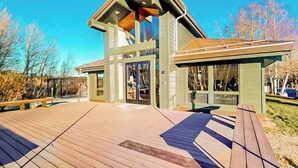 A modern building with a sloped roof, large glass windows, and a wooden deck. - Luxe, Modern Townhome w/ Mountain Views & WiFi - Close to Golf & Skiing (Mammoth Lakes)