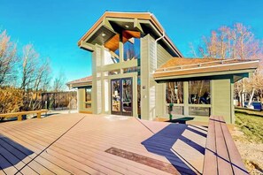 A modern building with a sloped roof, large glass windows, and a wooden deck. - Luxe, Modern Townhome w/ Mountain Views & WiFi - Close to Golf & Skiing (Mammoth Lakes)