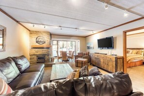 Ein großzügiger Wohnbereich mit Kamin, Ledersofas, einem Couchtisch und einem Fernseher.