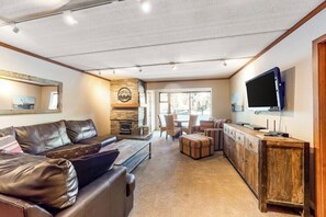 Ein geräumiges Wohnzimmer mit einer Ledersofa, einem Holzschrank und einem Fernseher.