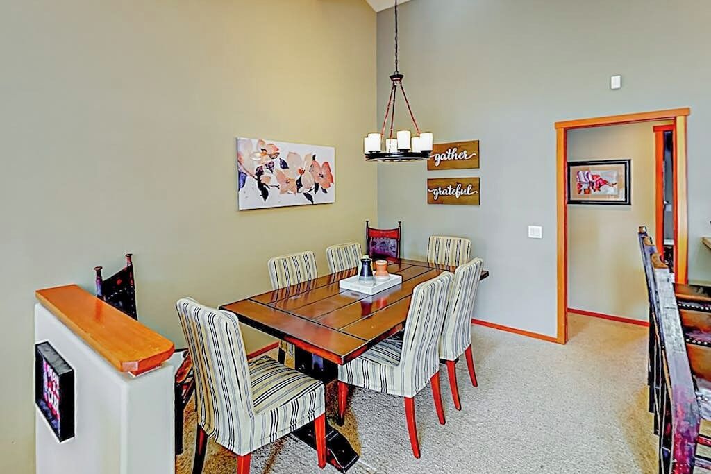 A dining area with a wooden table, striped chairs, and a chandelier.