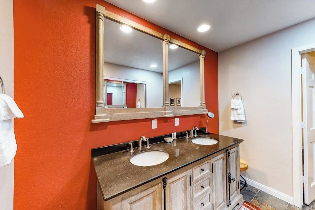 A bathroom with two sinks, a large mirror, and wooden cabinets.