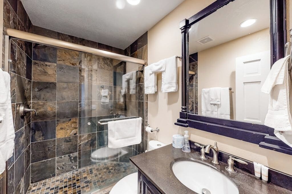 Un bagno moderno con doccia vetrata, un grande specchio e due lavandini.