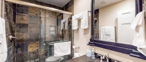 Un bagno moderno con doccia vetrata, un grande specchio e due lavandini.