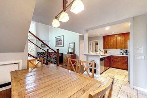 Eine geräumige Küche mit Holzausstattung, ein Essbereich mit Holztisch und -stühlen sowie eine Treppe, die in einen oberen Bereich führt.