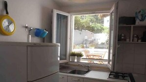 Eine kleine Küche mit Kühlschrank, Spüle und Fenster.