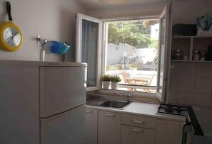 Eine kleine Küche mit Kühlschrank, Spüle und Fenster.
