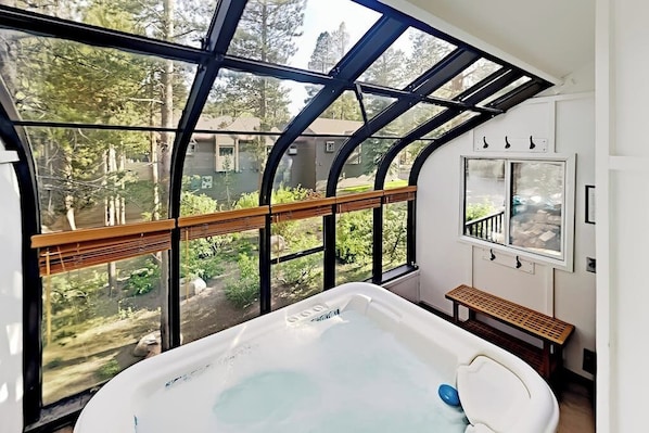 Ein Zimmer mit großem Fenster, einer Whirlwanne und einer hölzernen Sitzbank.