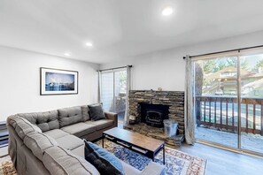 A living room with a sofa, fireplace, and large sliding glass doors. - Well-located condo with pool, hot tub, sauna, tennis - near golf & slopes (Mammoth Lakes)