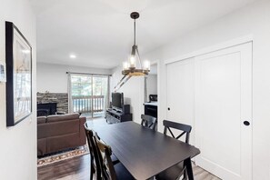 A modern kitchen with a dining table, chairs, a chandelier, and a television. - Well-located condo with pool, hot tub, sauna, tennis - near golf & slopes (Mammoth Lakes)