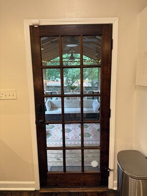 A dark wooden door with a glass panel, a white wall, and a small trash can to the right. - Charming, World Cup Ready 2-bedroom Bungalow in Ashford Park, Chamblee- Near PDK (Chamblee)