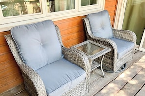 A wicker chair with a cushion and a small table in front of a wooden wall. - Home with Views, Shared Pool & Hot Tub - Near the Slopes (Mammoth Lakes)