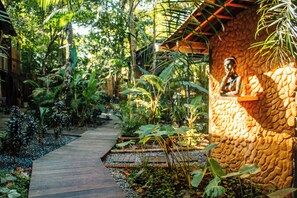 A garden pathway leading to a stone building with a statue. - Vila de Alter Pousada Boutique Amazônia (Santarém)