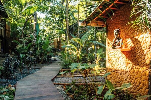 Un sendero en un jardín que lleva a un edificio de piedra con una estatua.