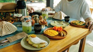 Una mesa de madera con diversos alimentos, un termo y un paraguas con lunares.