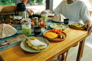 A wooden table with various food items, a thermos, and a polka-dotted umbrella. - Vila de Alter Pousada Boutique Amazônia (Santarém)