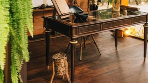 Una mesa de madera rústica con una lámpara negra, un cuadro enmarcado y una cesta de mimbre.