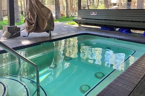 Ein Schwimmbecken mit Holzterrasse, einer überdachten Grillstelle und einem Rauchverbot-Schild.