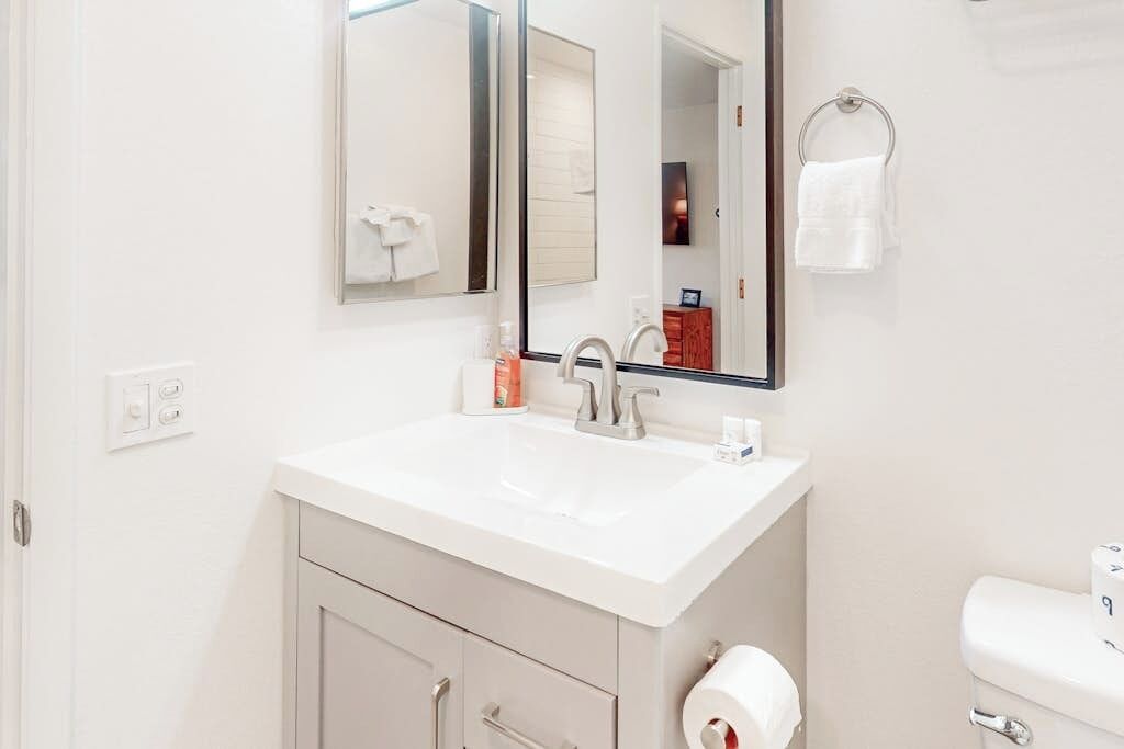 A bathroom with a white sink, mirror, and toilet.