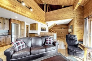 A wooden interior with a sofa, a chair, and a kitchen area. - Spacious condo near skiing with fireplace, washer/dryer, deck & full kitchen (Mammoth Lakes)