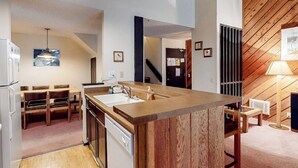 Eine moderne Küche mit Kochinsel, Holzboden und einem Essbereich mit Stühlen.