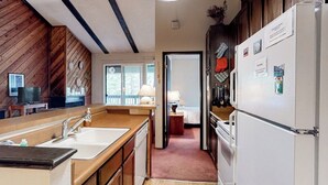 Eine Küche mit Holzwänden, einem weißen Kühlschrank und einem Waschbecken.