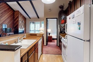 A kitchen with wooden walls, a white refrigerator, and a sink. - Comfy, lofted condo close to slopes with balcony, views, hot tub, & fireplace (Mammoth Lakes)