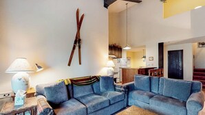 Ein Wohnzimmer mit einer Couch, einer Lampe und einem Paar Ski an der Wand.