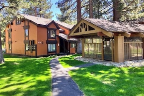 Eine zweistöckige Lodge mit einem Kiesweg, der zum Eingang führt, umgeben von Bäumen.