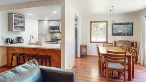 Una cocina moderna con armarios blancos, una isla central y taburetes de bar.